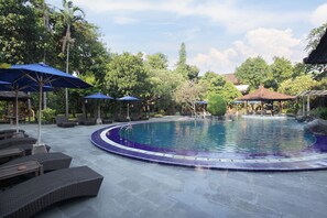 A pool area with lounge chairs and umbrellas, surrounded by trees and a gazebo. - Matahari Bungalow (Kuta)