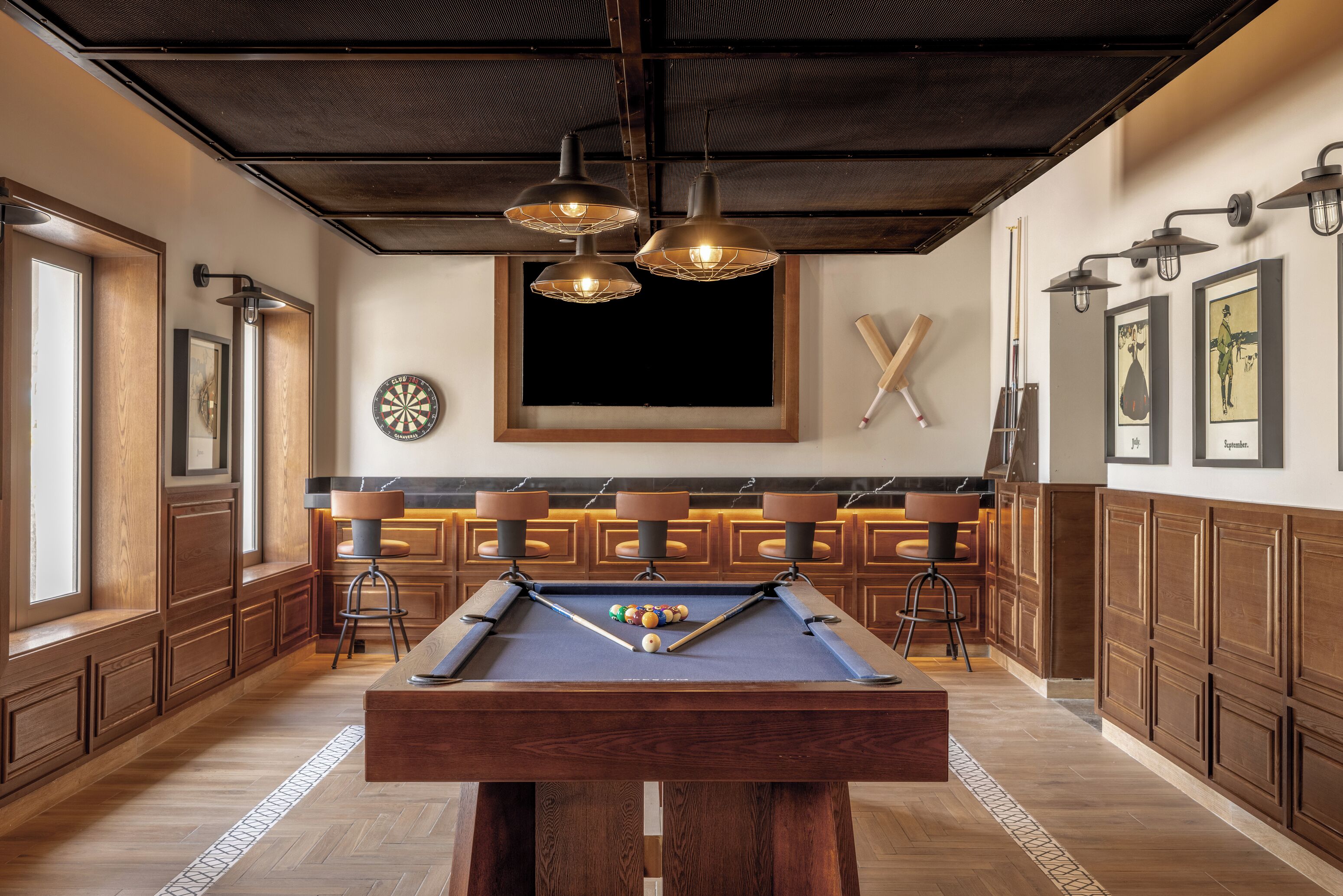 A billiards table with a pool cue and balls, wooden cabinets, and a dartboard on the wall.