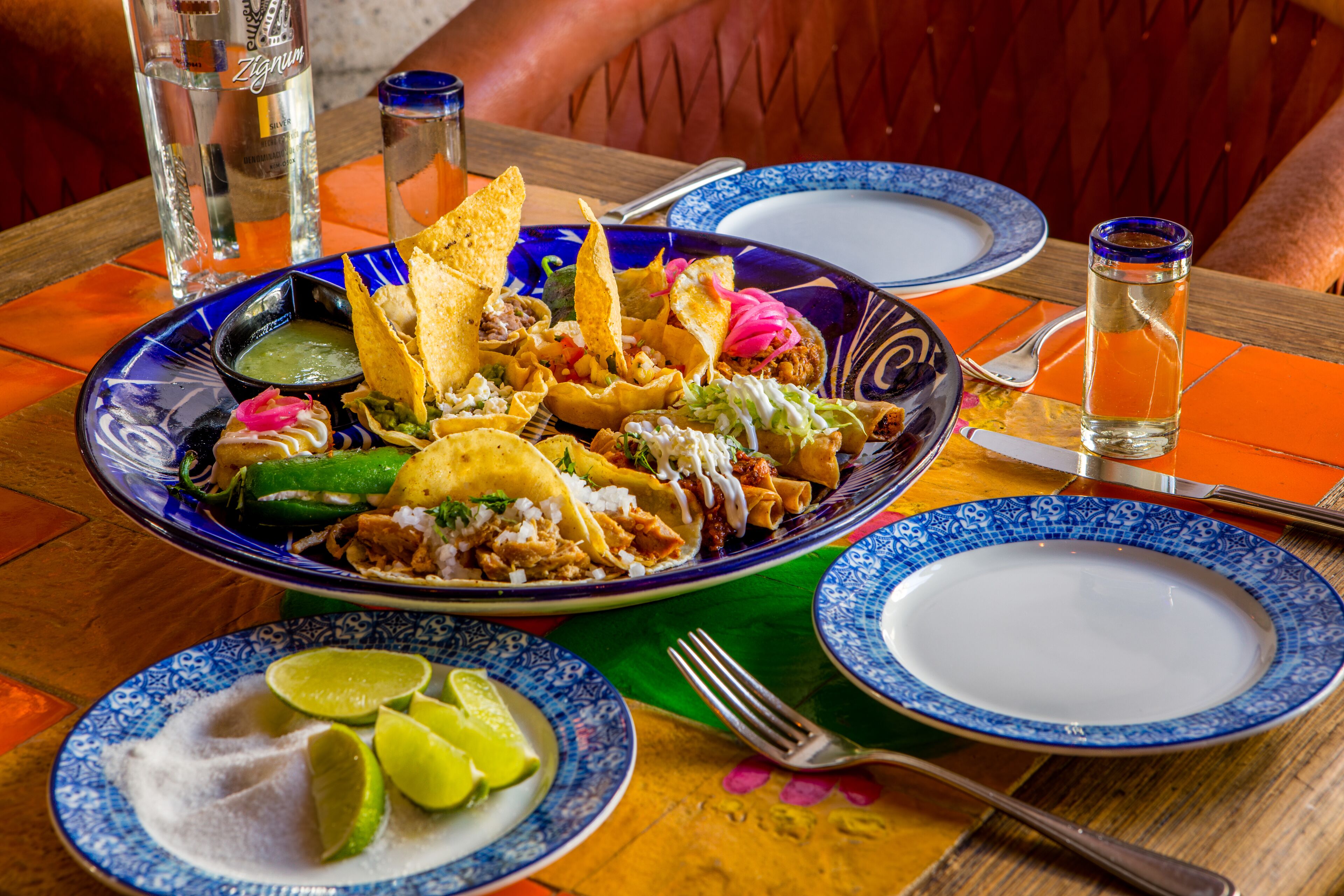 A table set with a blue and white patterned plate, a bowl of chips, and a glass of water.