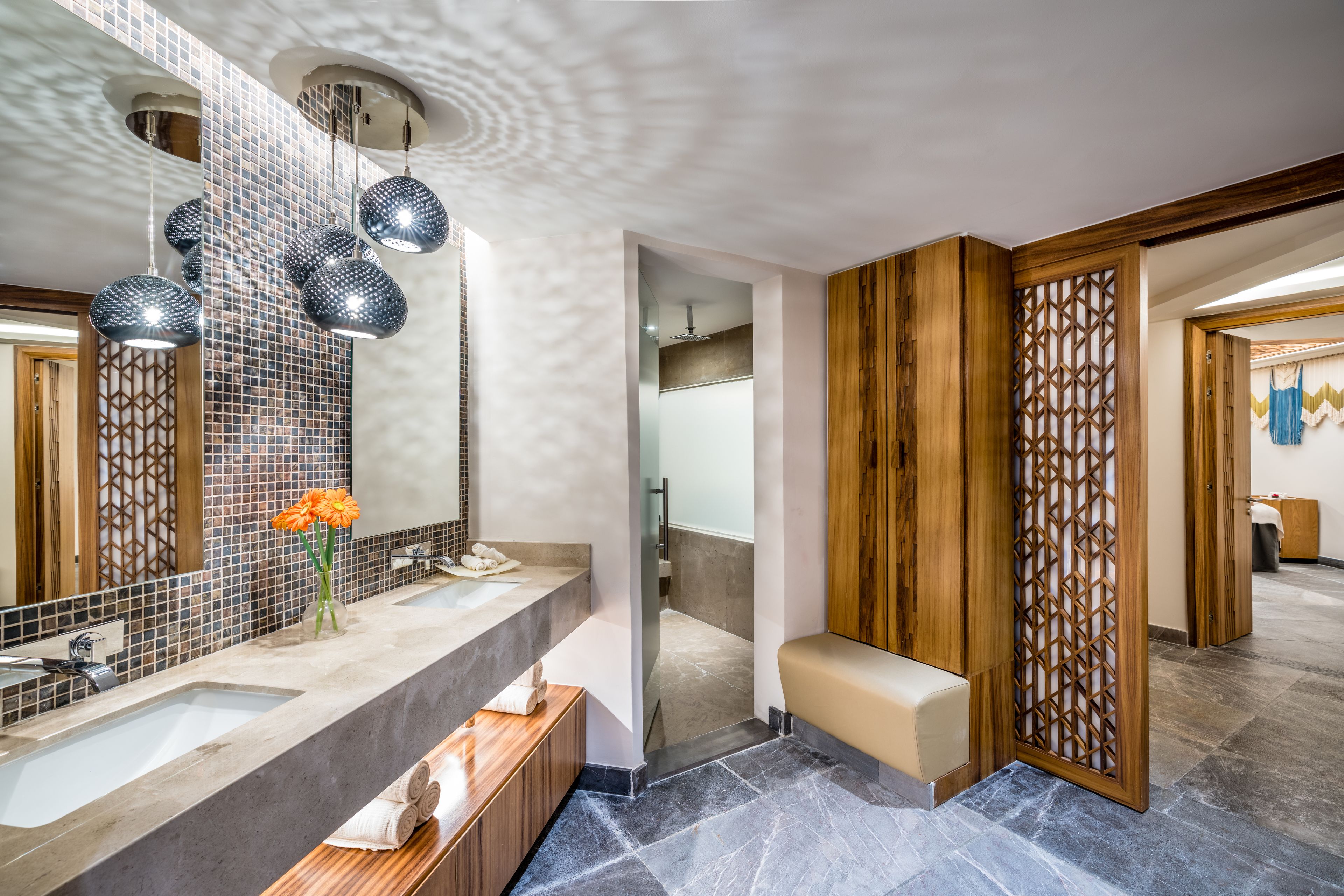 A modern bathroom with a large mirror, two sinks, and decorative hanging lights.