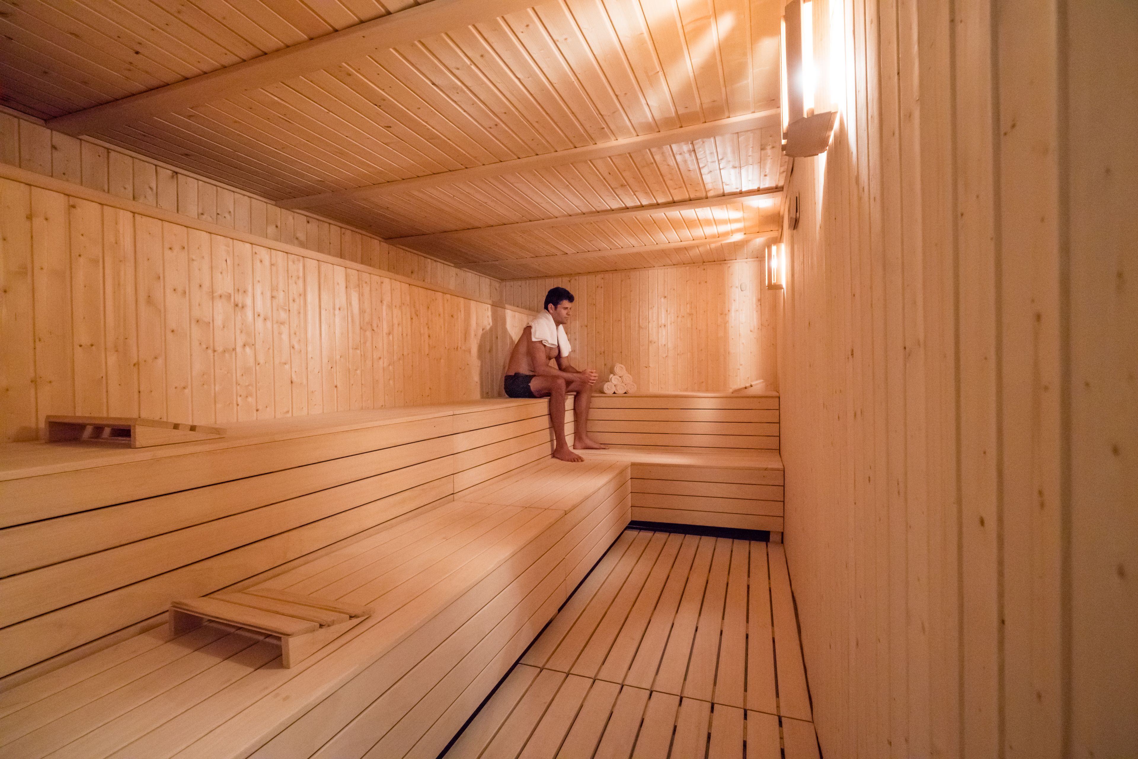 Una sauna con bancos de madera y una persona sentada en uno.