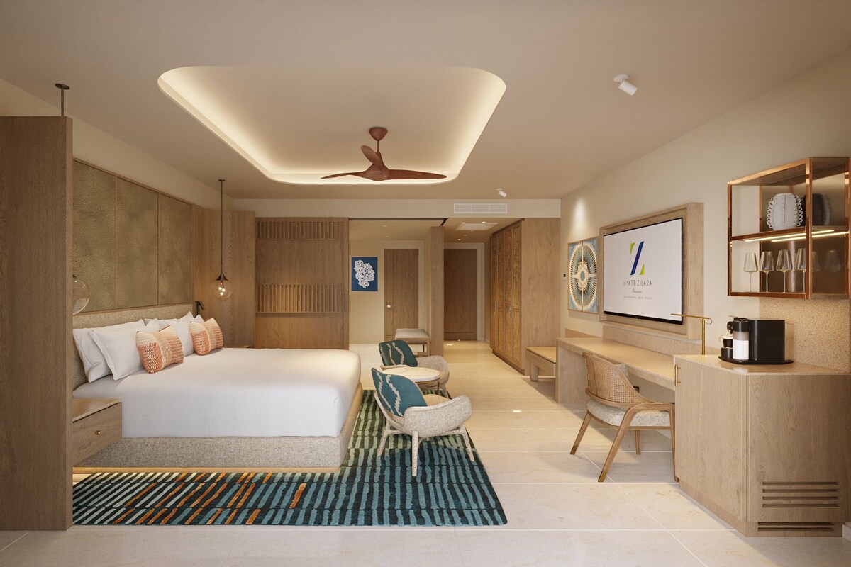 A modern hotel room with a large bed, a desk, and a television.