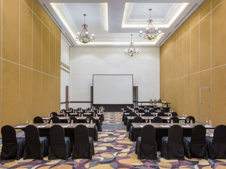 A conference room with tables, chairs, and a projector screen.