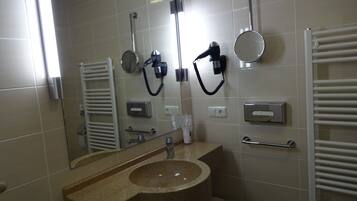 A bathroom with a sink, mirror, towel rack, and a hairdryer.