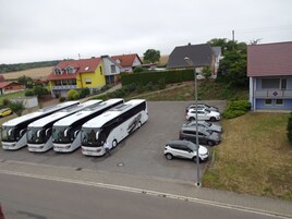 Un estacionamiento con varios autobuses y automóviles estacionados.