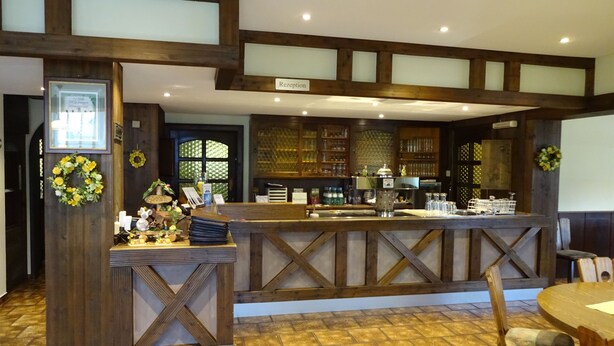 A reception area with a wooden reception desk, a reception sign, and a counter with various items. - Gasthof Hotel Zum Ross (Wertheim)
