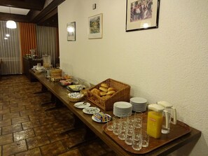 Un buffet proposant une variété de plats et de boissons, une longue table en bois et un sol à motifs.