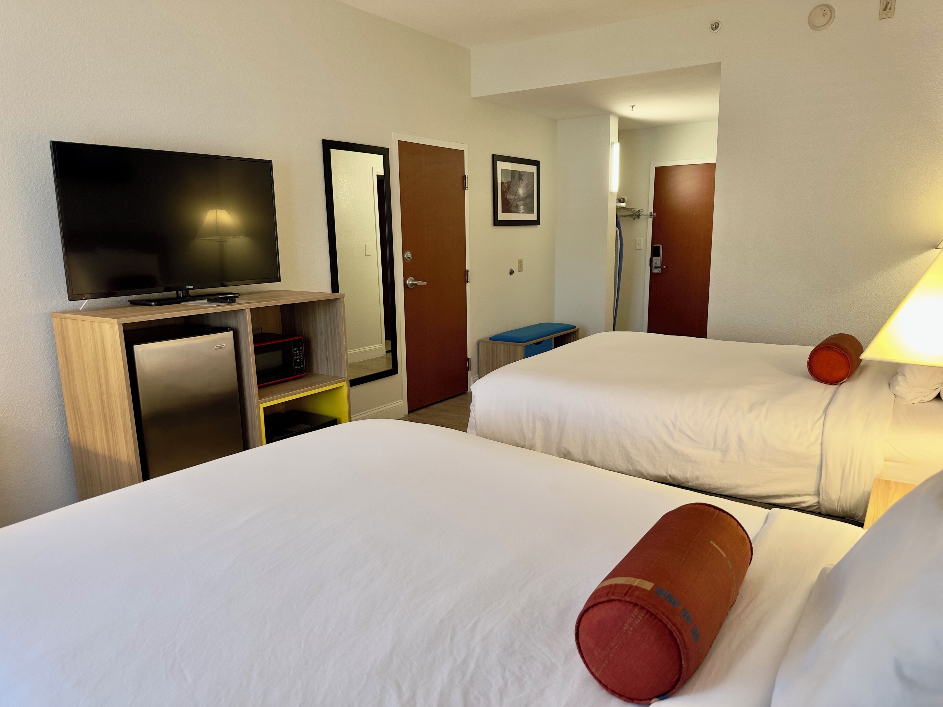 Habitación de hotel con dos camas, televisión, microondas y escritorio.