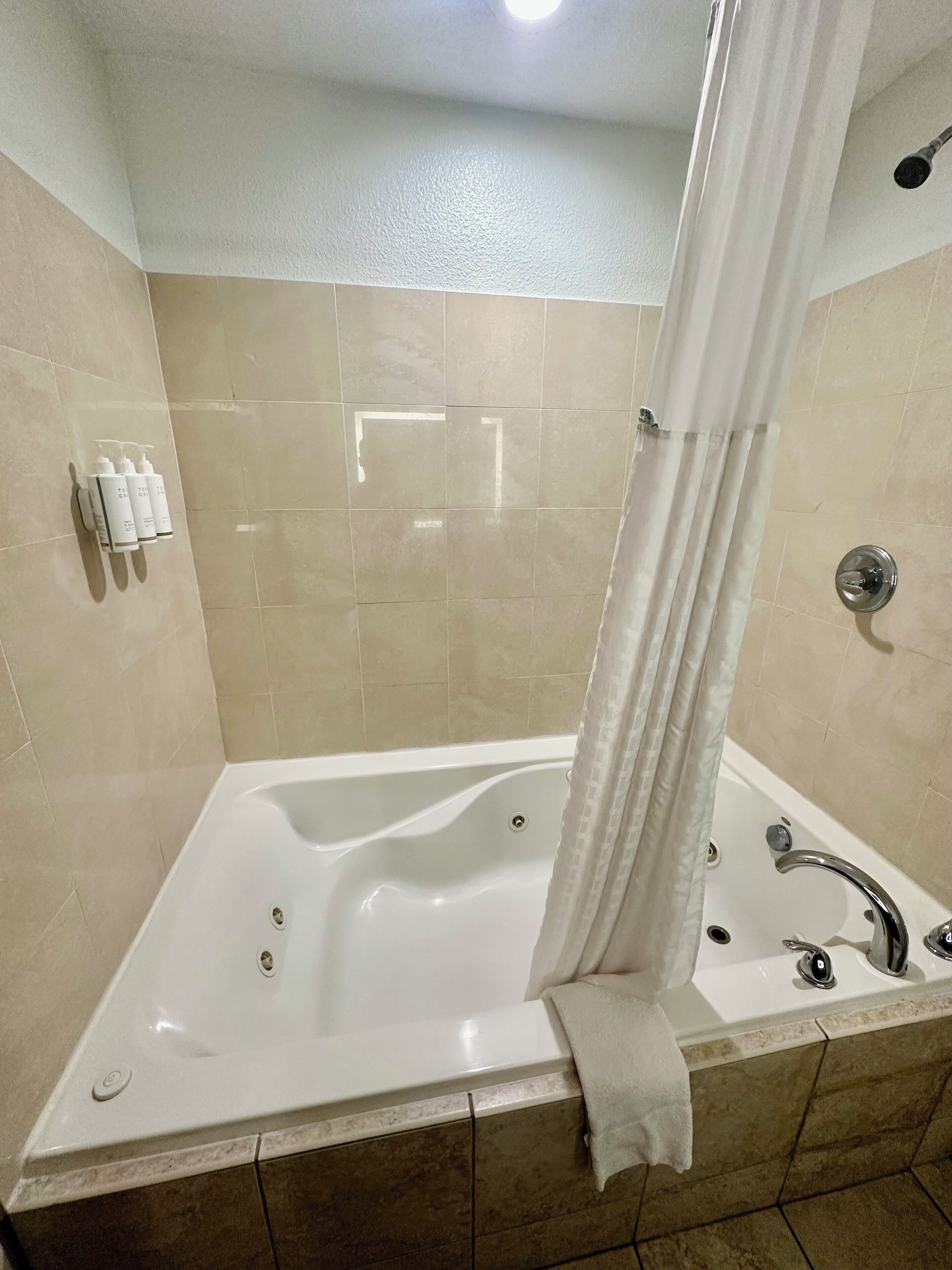 Un baño moderno con una bañera independiente, cortina de ducha y un perchero con artículos de aseo.