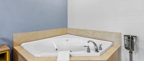 Ein Badezimmer im Eckbereich mit freistehender Badewanne, Waschbecken und Handtuchhalter.