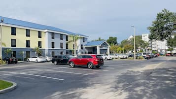 Un estacionamiento con varios automóviles y un edificio de techo azul y paredes amarillas.