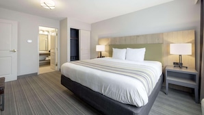 Ein Hotelzimmer mit einem großen Bett, zwei Nachttischen mit Lampen, einem Holzkopfschild und einem Teppichboden.