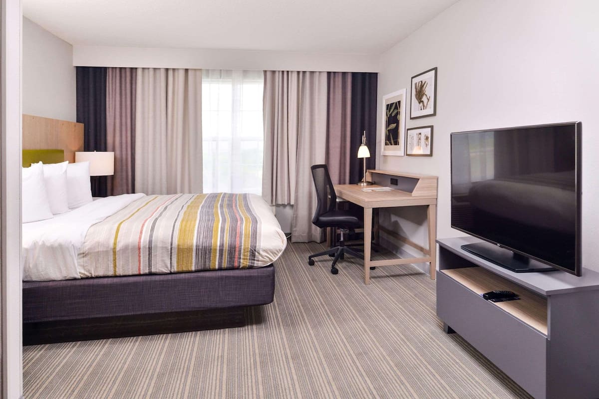 Une chambre d’hôtel équipée d’un lit, d’un bureau, d’une chaise, d’une télévision et de rideaux.