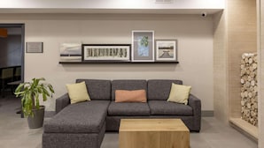 Ein modernes Wohnzimmer mit einem grauen Ecksofa, einem Holztisch und einer Zimmerpflanze.