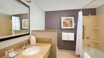 A modern bathroom with a granite sink, a large mirror, a bathtub, and a shower curtain.