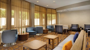 A hotel lobby with a patterned carpet, seating areas with sofas and armchairs, and large windows with curtains. - Courtyard by Marriott San Antonio Lackland (San Antonio)