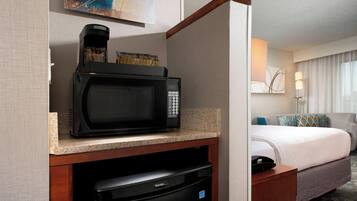 Una kitchenette compacta con microondas, cafetera y lavavajillas.