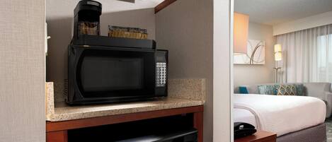 A compact kitchenette with a microwave, coffee maker, and dishwasher.