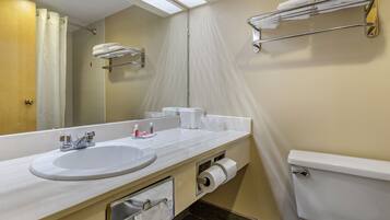 Un baño con lavamanos, espejo, toallero, inodoro y cortina de ducha.