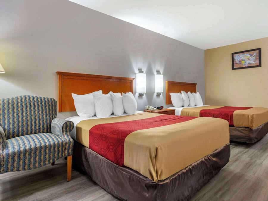 A hotel room with two beds, a chair, and a nightstand.