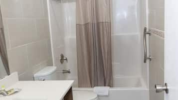 A bathroom with a toilet, sink, and shower area.