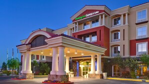 A hotel with a prominent entrance, a covered patio area, and a sign indicating it is a Holiday Inn Express & Suites.