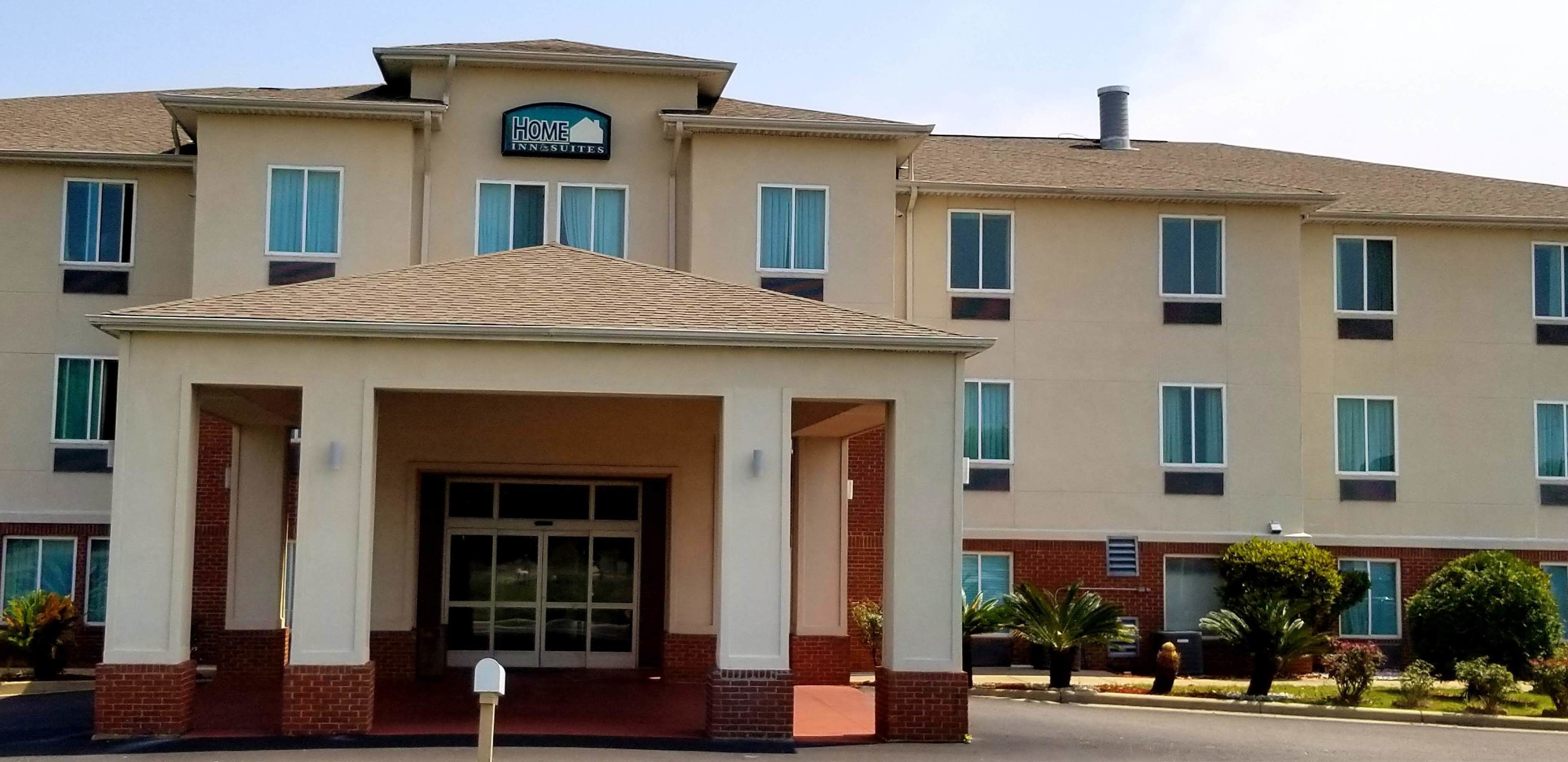 A hotel with a central entrance, multiple windows, and a sign indicating it is a home inn.