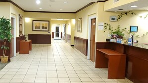 A hotel lobby with a reception desk, a plant, a bench, and a tiled floor. - Home Inn & Suites (Montgomery)