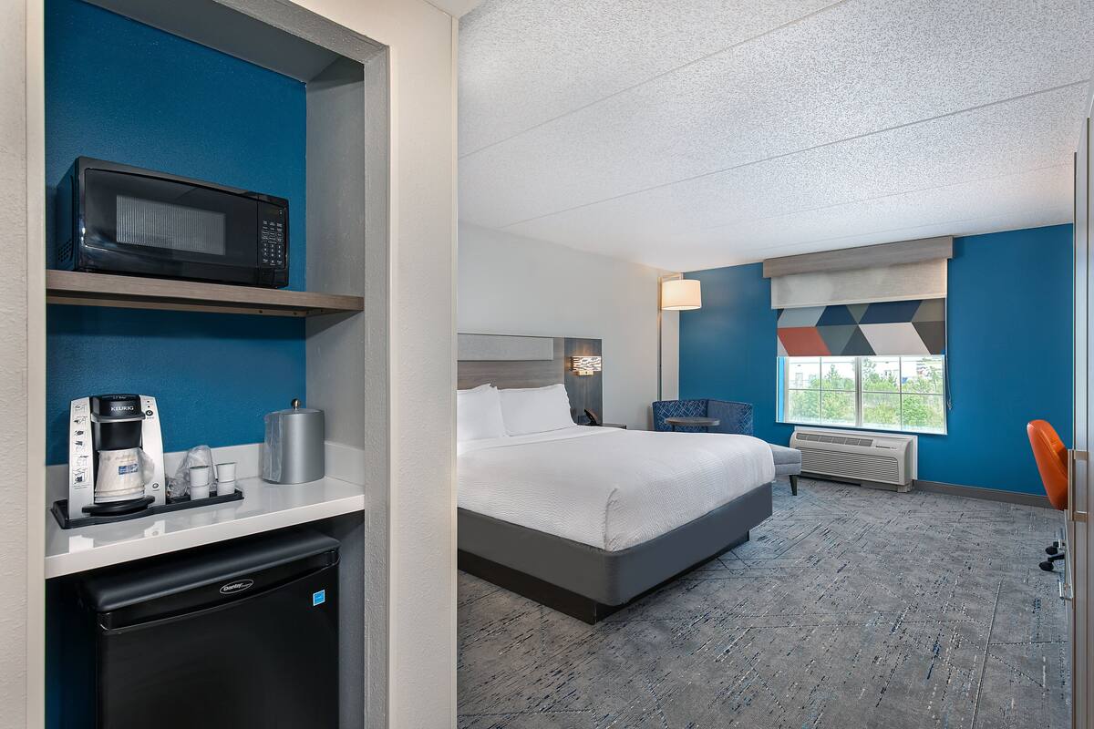 Ein Hotelzimmer mit Bett, Mikrowelle, Kaffeemaschine und kleinem Kühlschrank.