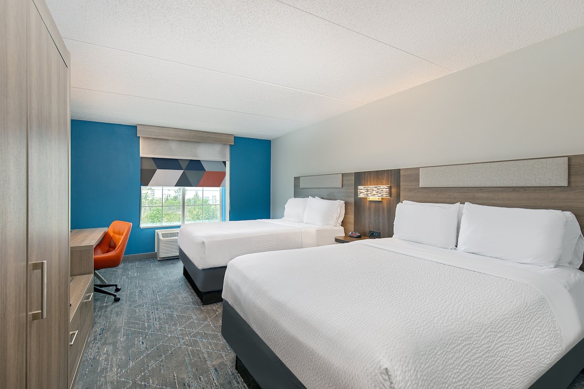 Ein Hotelzimmer mit zwei Betten, einem Schreibtisch und einem Stuhl.