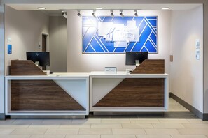 Een receptiebalie met een modern design, met twee computerwerkplekken en een groot blauw geometrisch kunstwerk erboven.