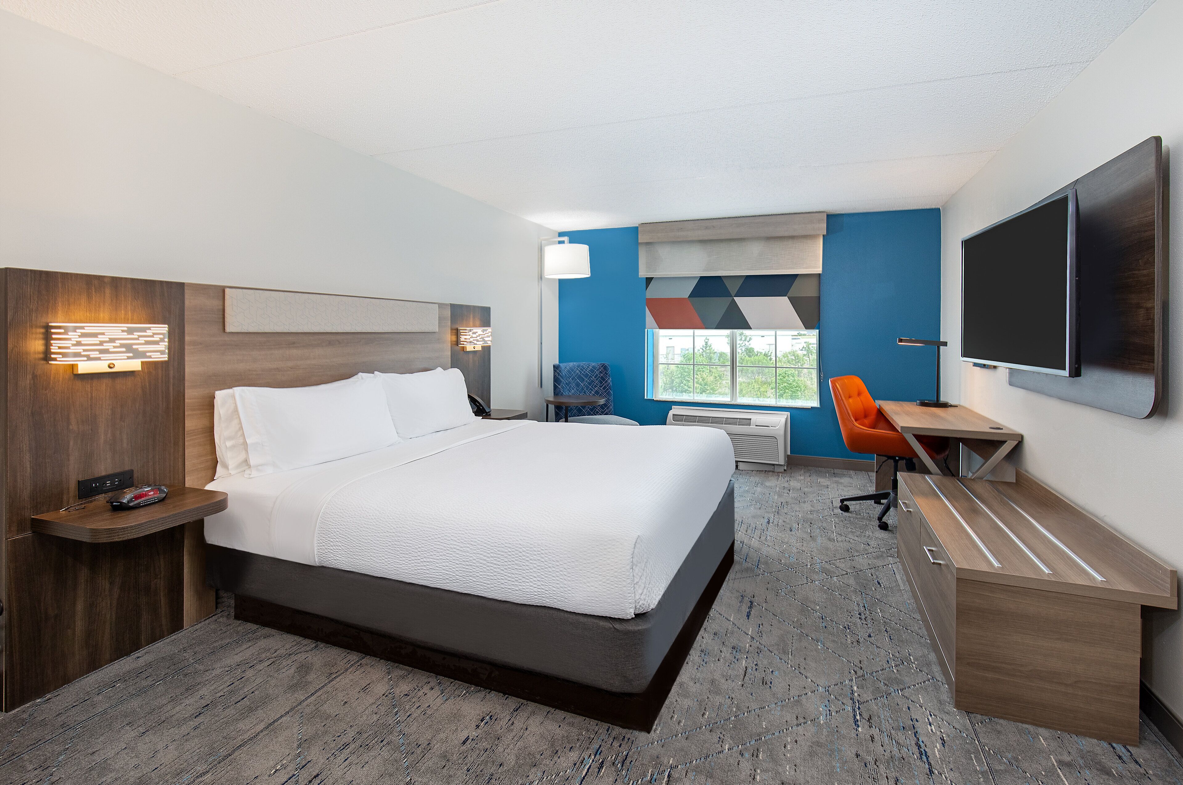 Une chambre d’hôtel avec un grand lit, un bureau, une chaise, une télévision et une fenêtre donnant sur un beau paysage.