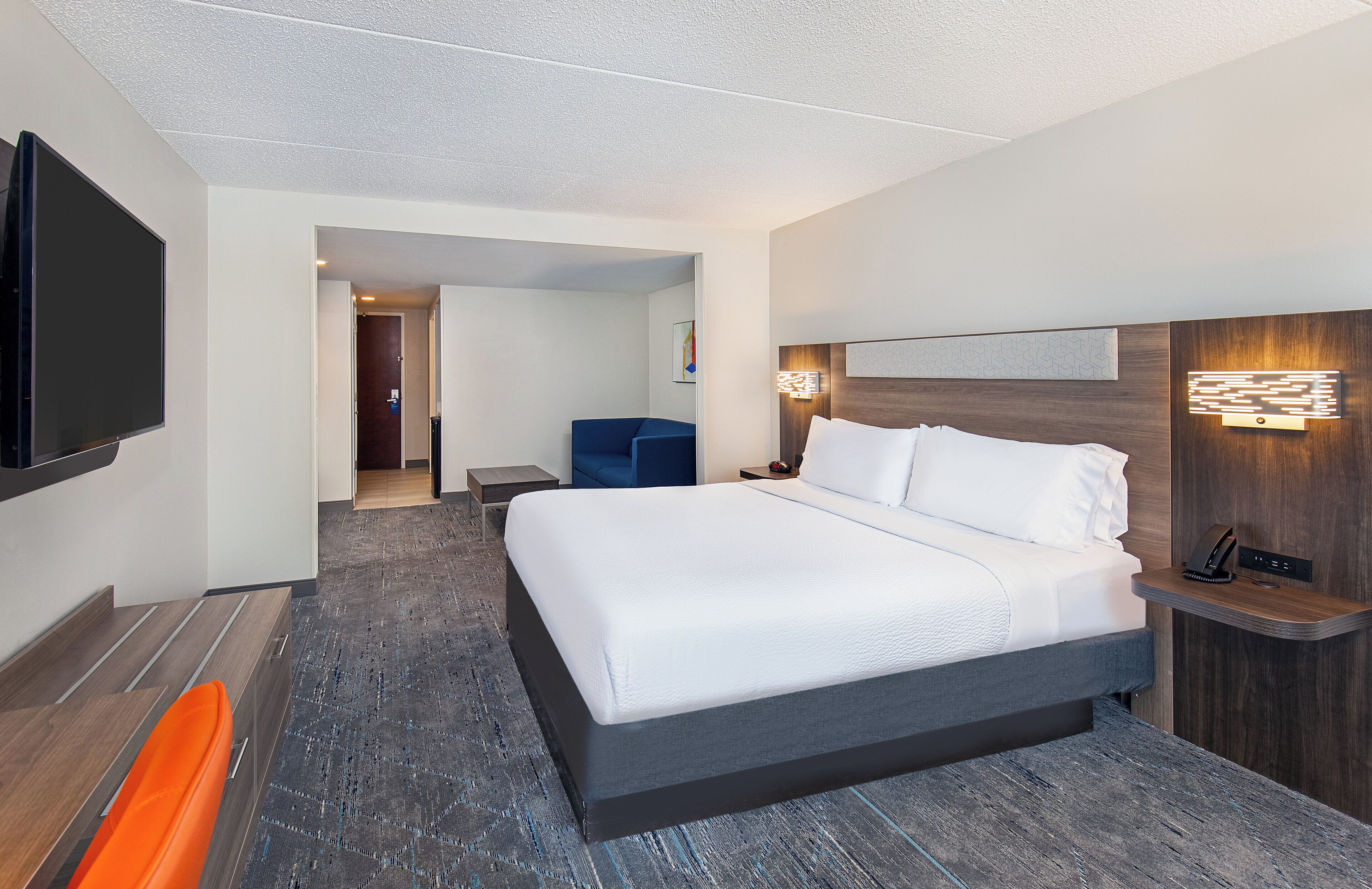 A hotel room with a large bed, a flat-screen TV, a desk, and a chair.
