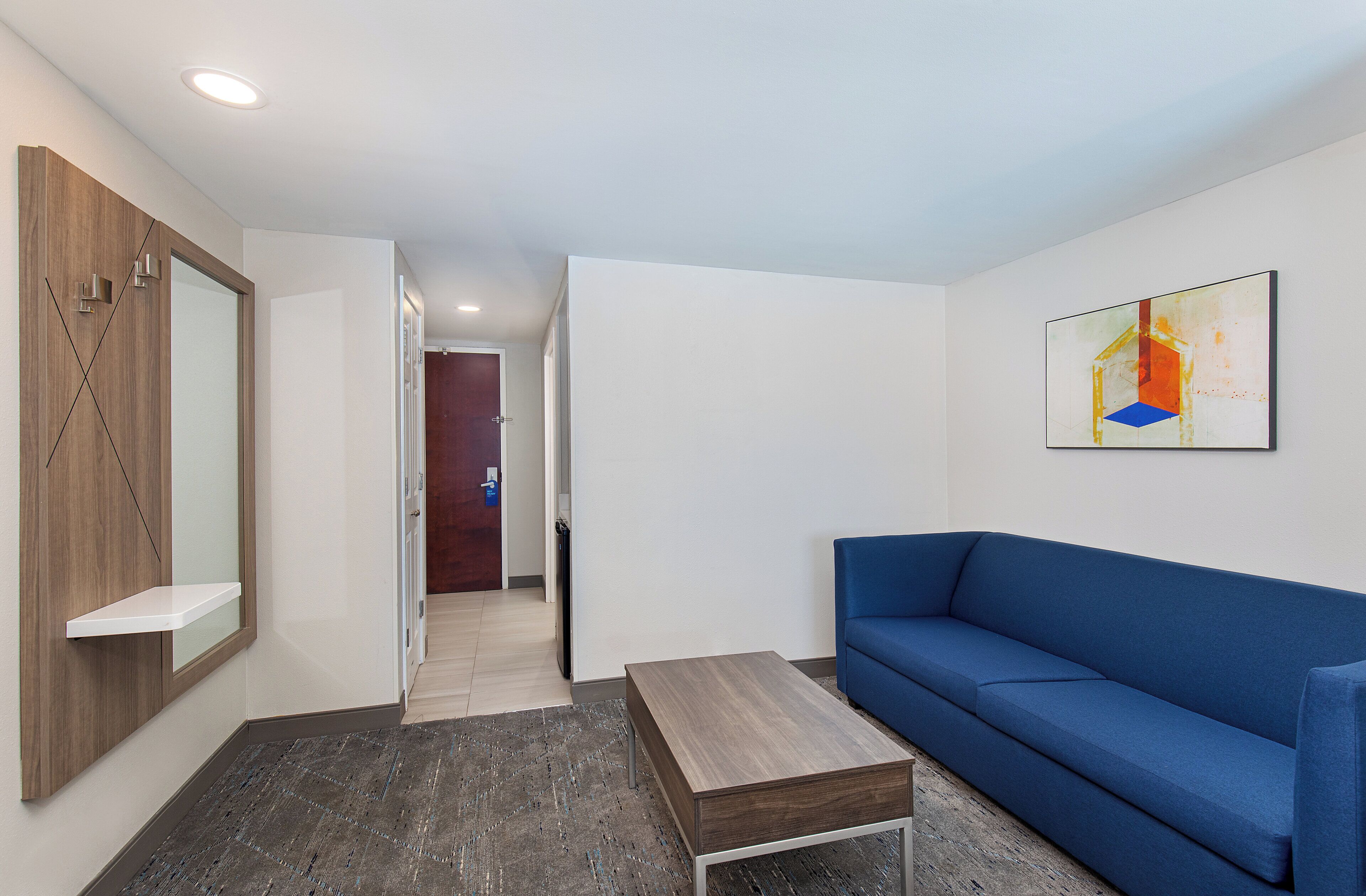 Un salon moderne avec un canapé bleu, une table basse en bois et un tableau accroché au mur.