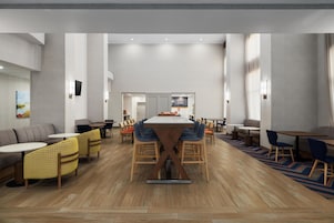 Uma área de refeições moderna com uma mesa comprida no centro, diversas opções de assento e vista para a cozinha.