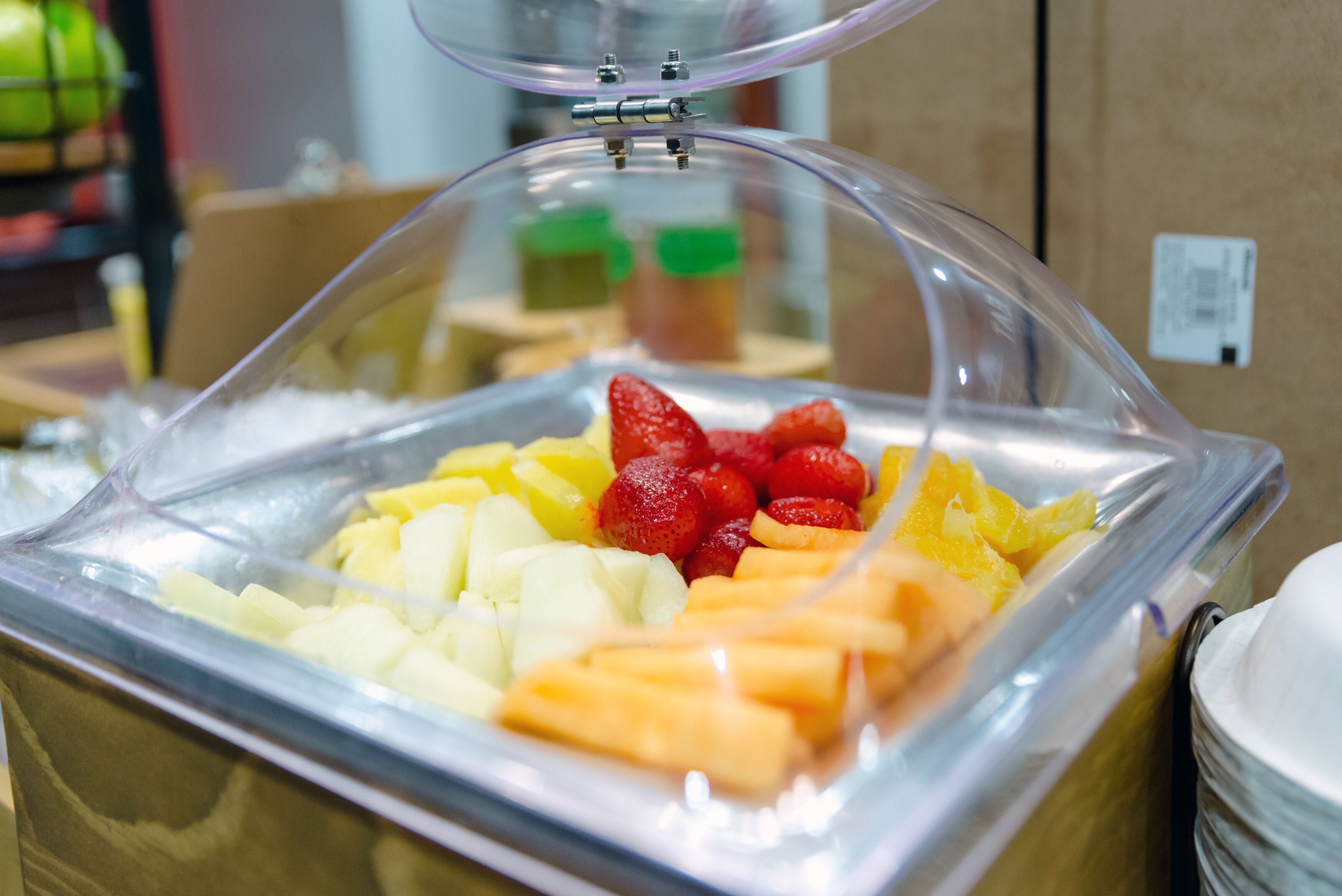 A food display with fruits and a clear plastic cover.