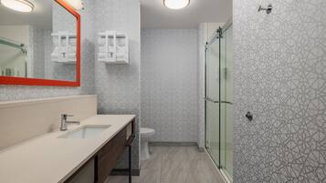 A modern bathroom with a large mirror, a sink, a toilet, and a shower area.