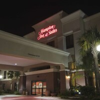Edificio de Hampton Inn & Suites con un letrero de neón, entrada despejada y un letrero de altura libre de 3.8 metros.