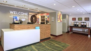 Un'area reception di un hotel con una scrivania centrale, una sveglia e un angolo caffè.