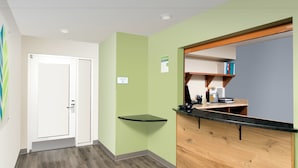 A hallway with a reception desk, a no-smoking sign, and a door.
