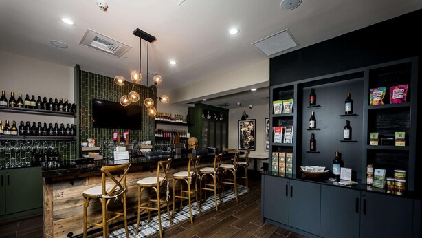 Un coin bar avec des chaises en bois, un téléviseur et des étagères remplies de bouteilles.