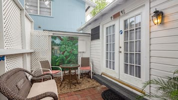 A patio with wicker furniture, a glass table, and chairs.