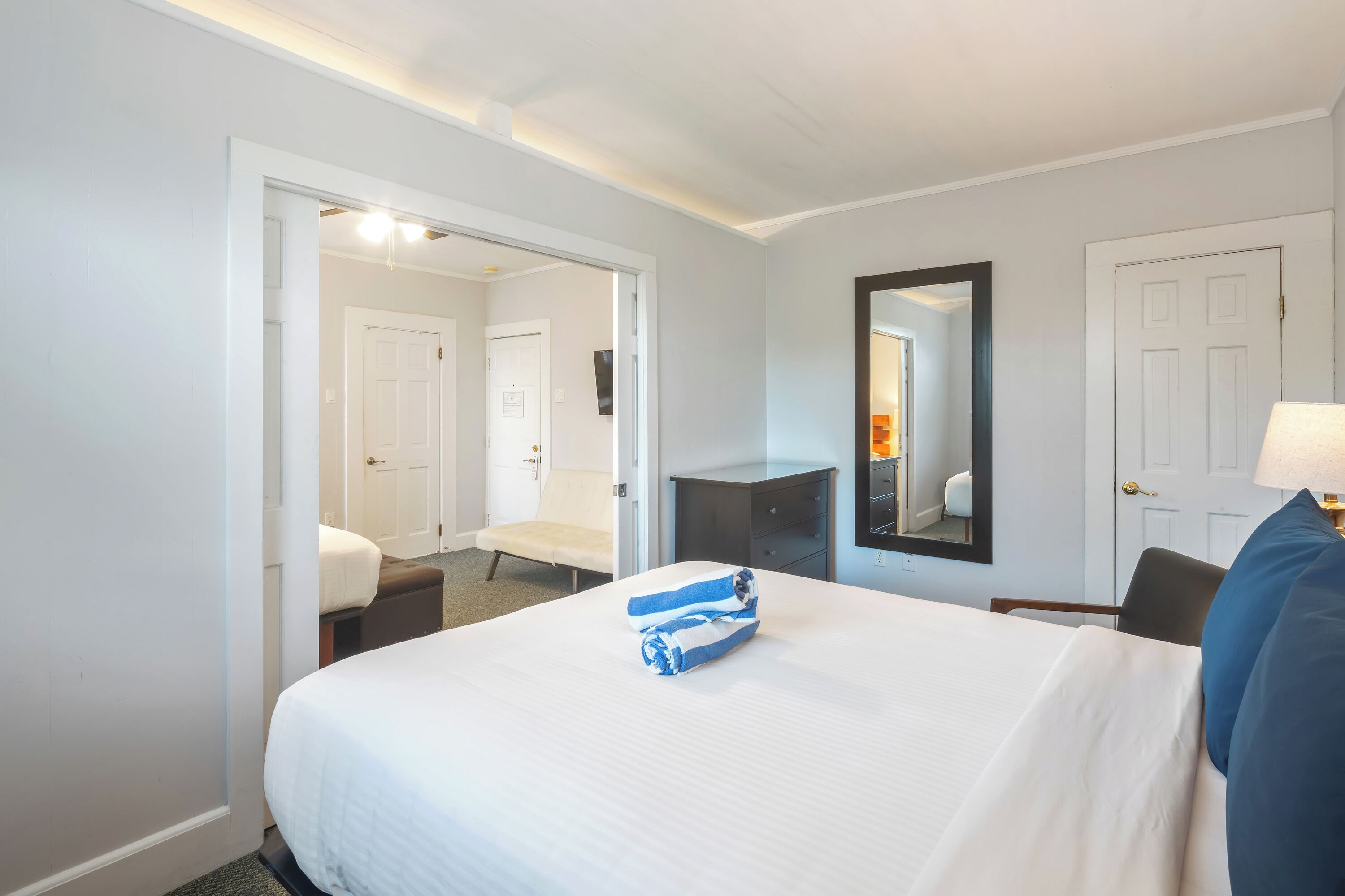 Een hotelkamer met een groot bed, een bureau, een stoel, een spiegel en een deur.