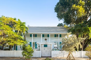 A white building with green shutters, a white picket fence, and a star on the front.
