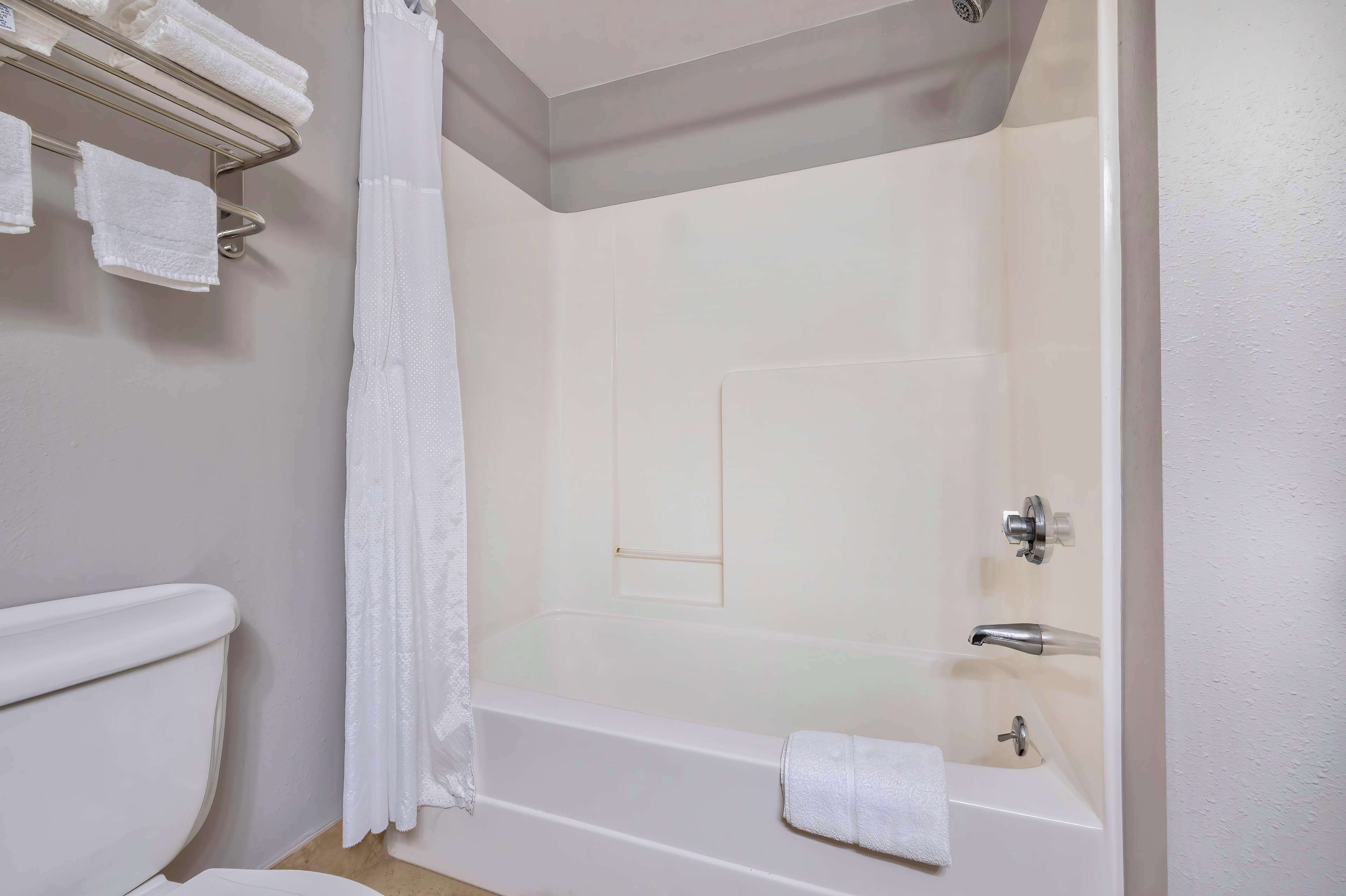 A bathroom with a bathtub, a toilet, and a towel rack with towels.