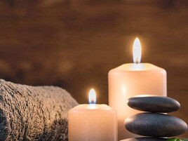 Duas velas acesas e uma pilha de pedras lisas.