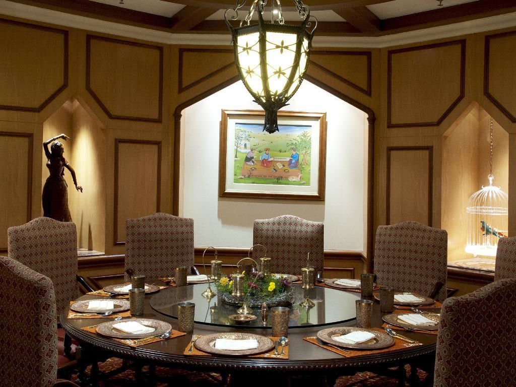 A conference room with a round table, patterned chairs, a chandelier, and a framed painting on the wall.