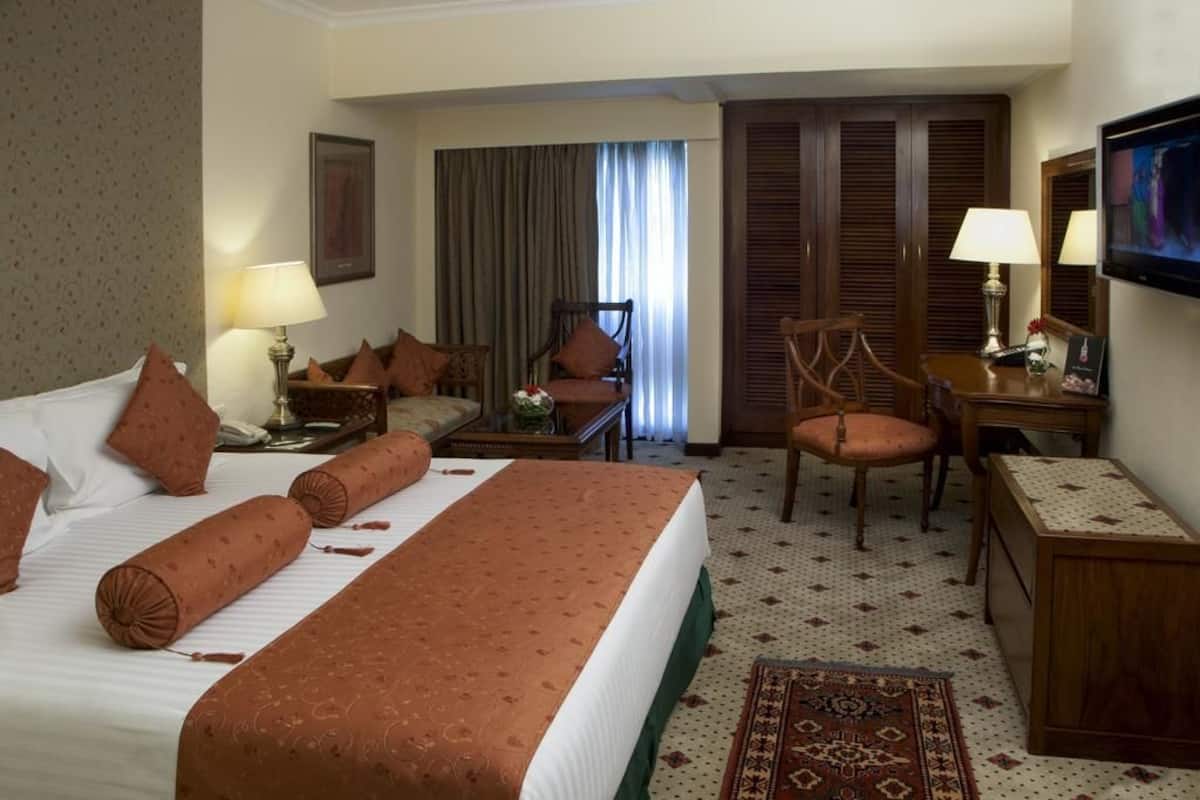 Una habitación de hotel con una cama grande, un escritorio, una silla y un televisor.