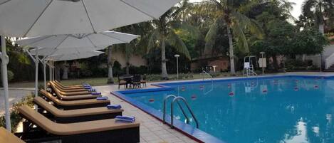 Un área de piscina con sillones de descanso y sombrillas.