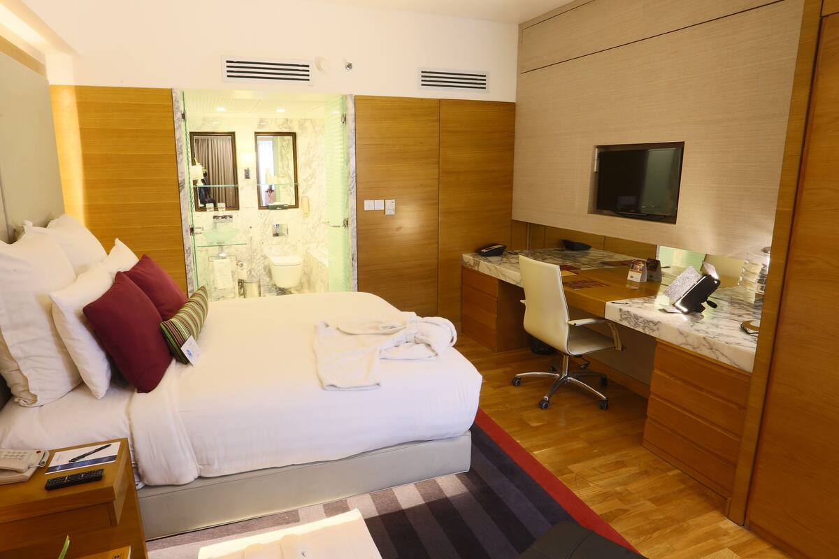 Ein Hotelzimmer mit Bett, Schreibtisch, Fernseher und einem durchgegangenen Tür erkennbaren Badezimmer.